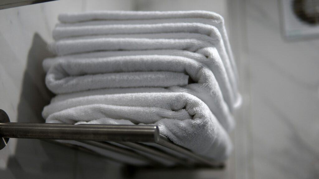 Stack of folded white towels on a chrome rail against a marble wall